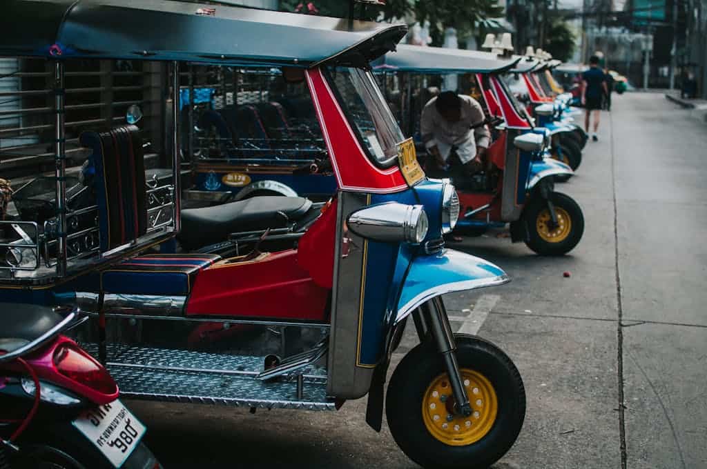 Colorful tuk tuks parked in a row on an urban street, emphasizing transportation culture.